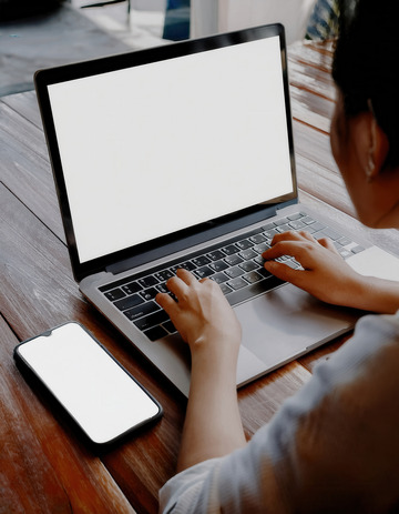 人在桌前使用电脑和空白屏手机