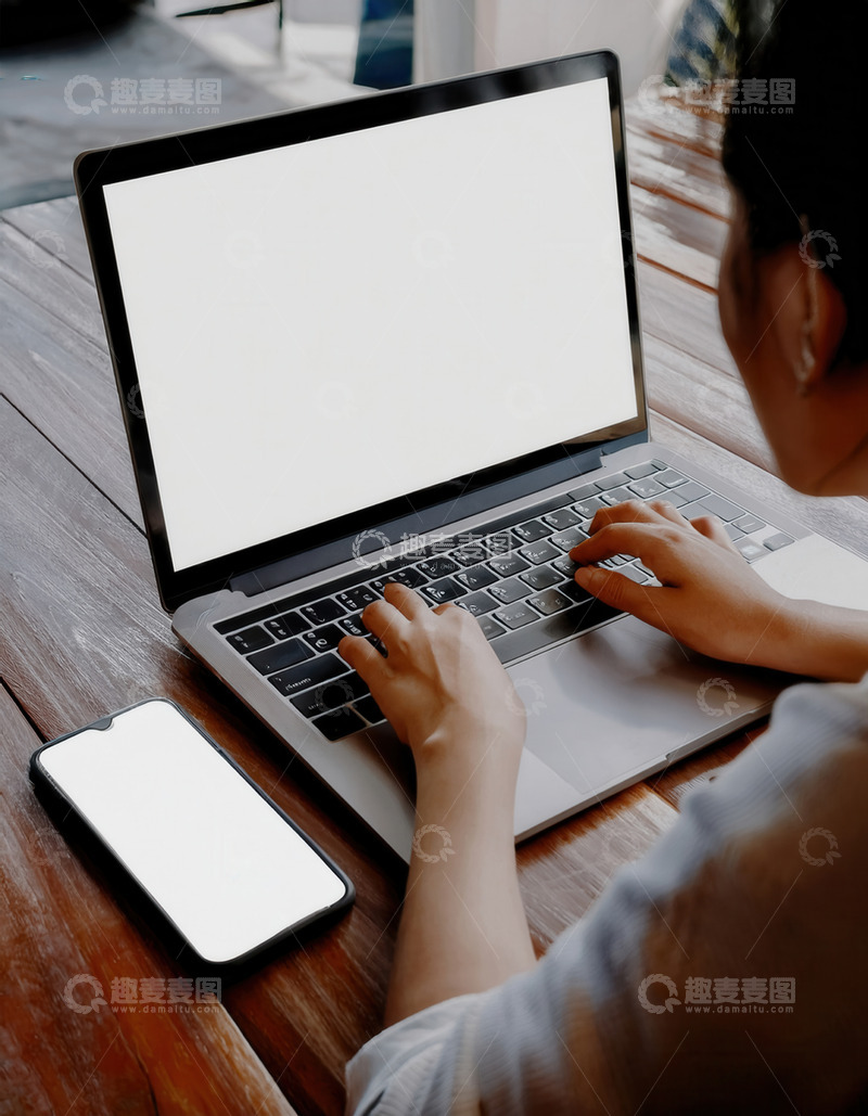 人在桌前使用电脑和空白屏手机