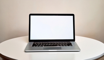 白色圆桌上的空白屏笔记本电脑