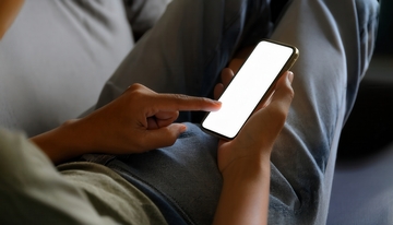 人坐沙发上手触亮屏智能手机