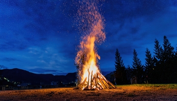 夜幕下山林旁熊熊燃烧的篝火