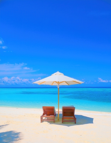 马尔代夫沙滩上伞下静候的休闲躺椅
