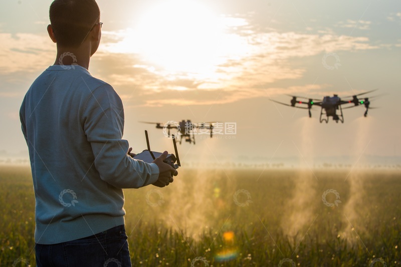高清大图下载【趣麦麦图】日落时分操作无人机在农田上空进行施药施肥作业
