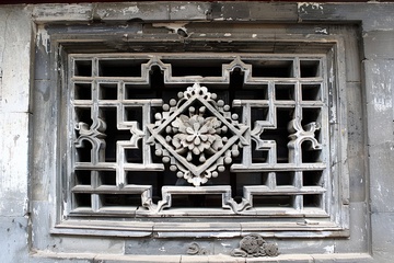 青砖墙体上雕刻的花窗