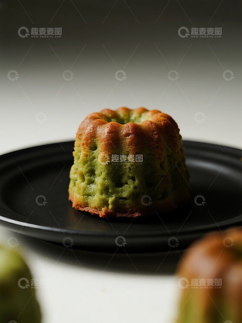 高清大图下载【趣麦麦图】法式抹茶味可露丽蛋糕，置于黑色盘中