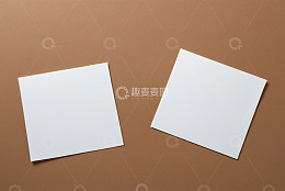棕色背景上的两张空白方形纸张