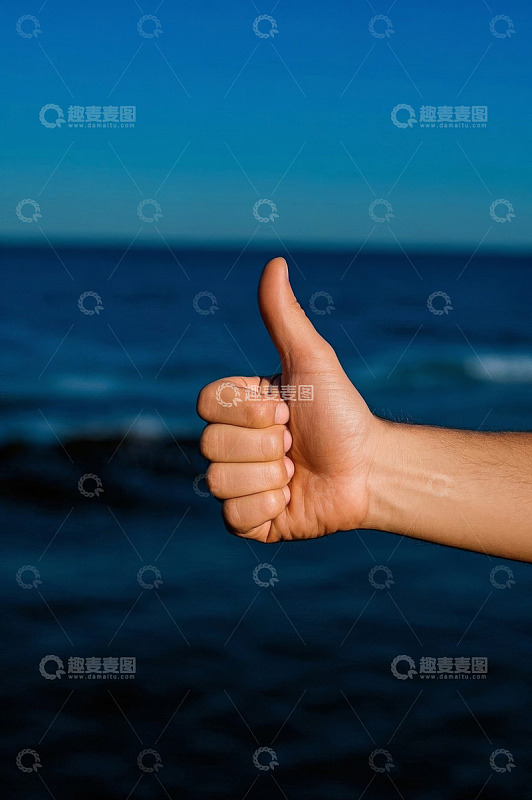 海边竖大拇指的手部特写