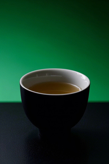 黑杯盛茶配绿色背景