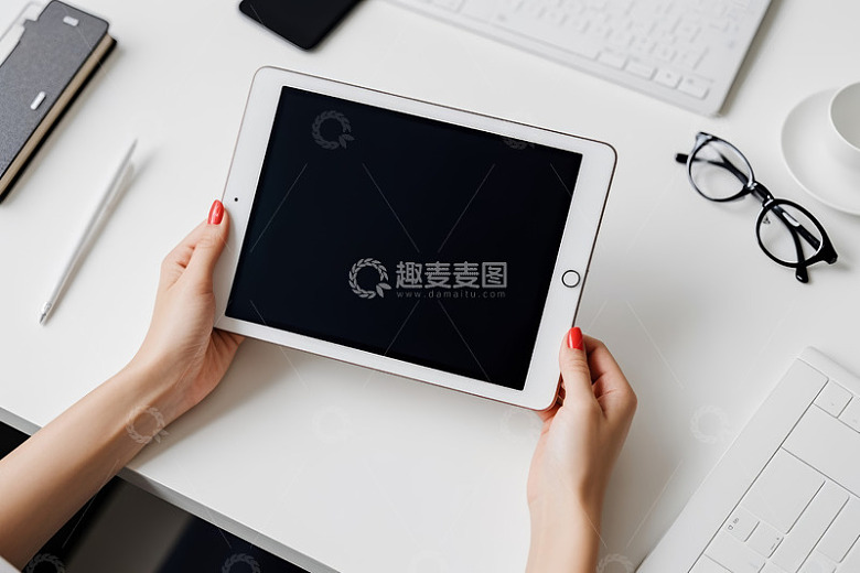 女性在办公桌前手持平板电脑