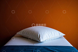 橙色墙边床与白色枕头