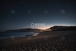夜晚海滩与远处山景及灯火