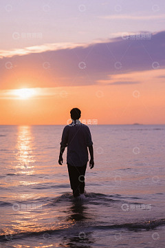 男子在海边踏浪迎夕阳