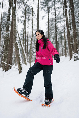女子雪地穿雪鞋漫步森林