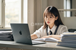 女生坐在桌前使用笔记本电脑学习