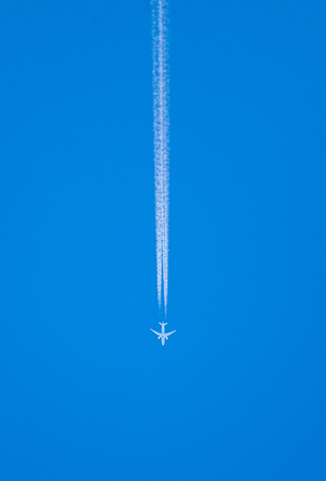 划破蔚蓝天空飞机白色航迹摄影图
