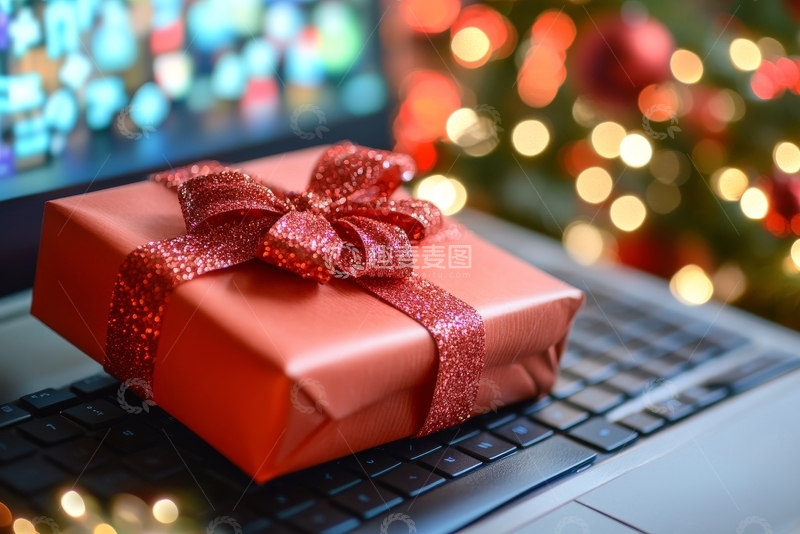 高清大图下载【趣麦麦图】红色礼盒置于笔记本电脑上，背景为圣诞树