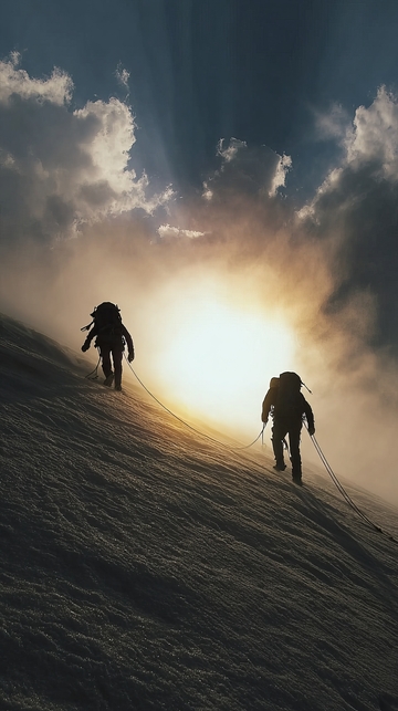 登山者在雪坡上向阳光前进