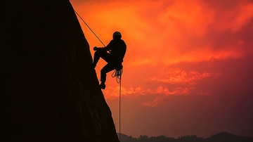 攀岩者在夕阳下攀登峭壁