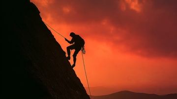攀岩者在夕阳下攀登峭壁