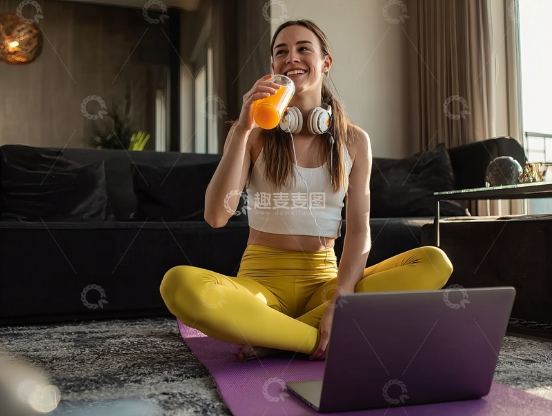 女子在瑜伽垫上喝饮料微笑