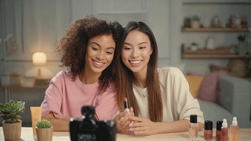 两位女性在室内环境中展示美甲产品并微笑