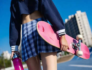 年轻女性手持滑板和水瓶站在户外