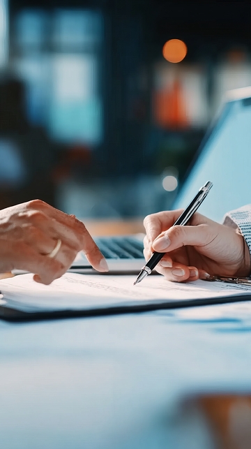 一人在笔记本电脑旁用笔书写文件