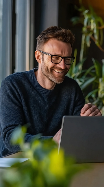 微笑男子在室内使用笔记本电脑