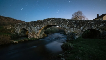 夜晚石桥横跨河流水面倒映灯光