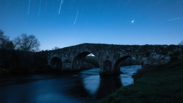 夜幕下石桥横跨河流流星划过天际