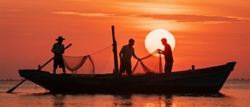 渔民在日落时分于海上收网作业