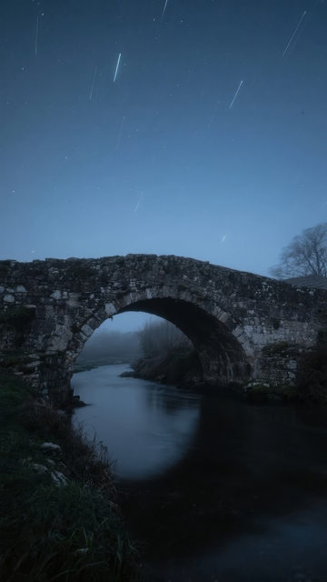 夜空下拱桥倒映水中流星划过