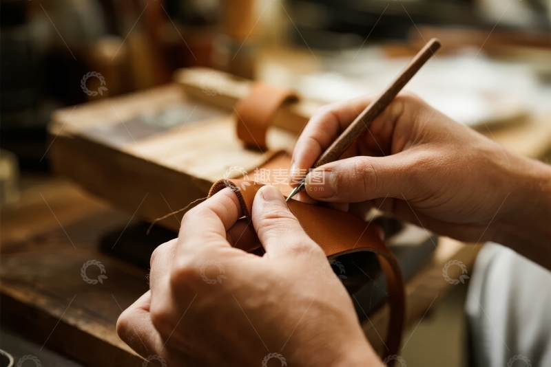 高清大图下载【趣麦麦图】工匠在工作台上用工具细致缝制皮革制品