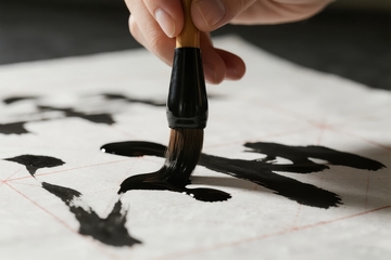 手握毛笔在宣纸上书写书法