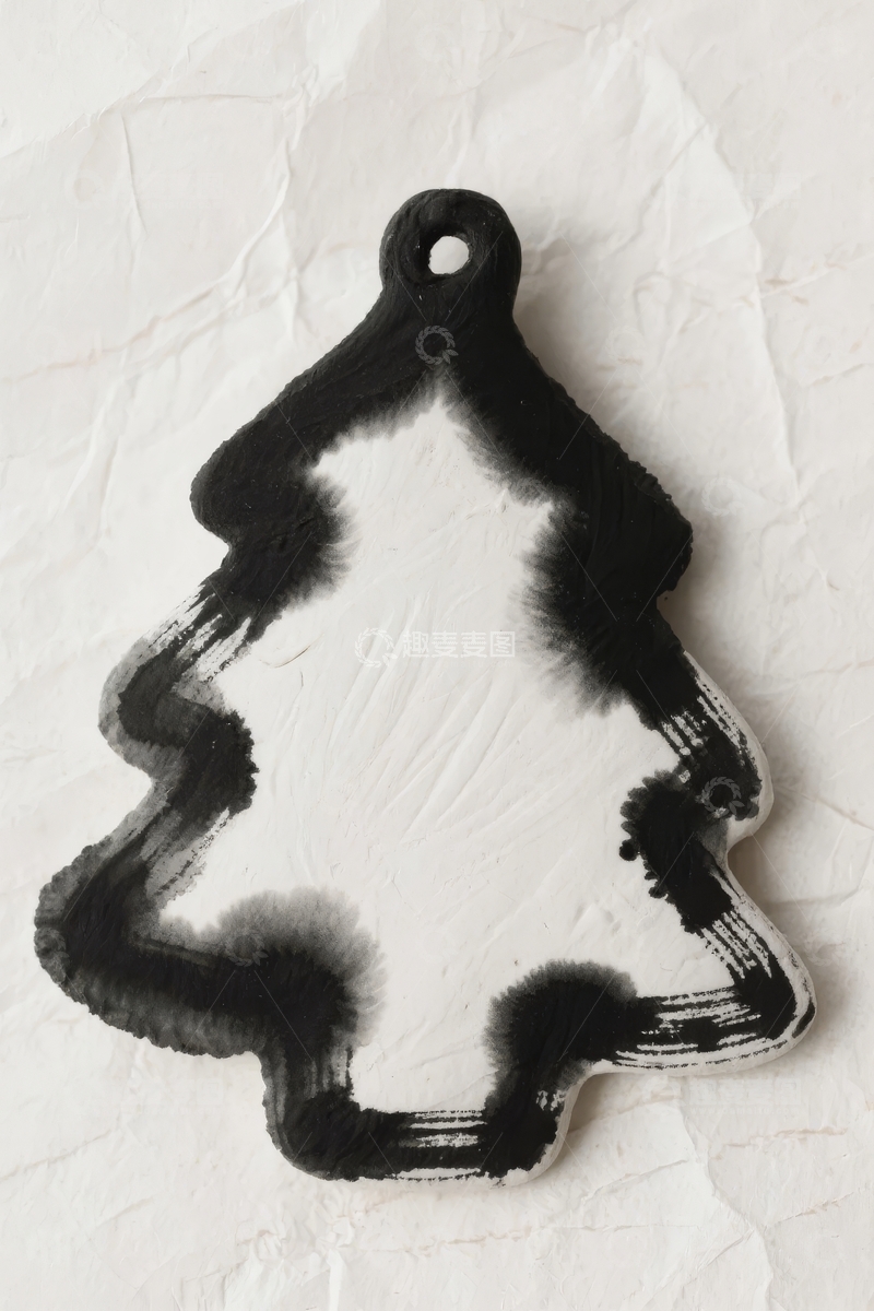 高清大图下载【趣麦麦图】黑色圣诞树形状装饰品置于褶皱纸张背景上