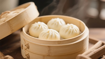 竹制蒸笼中摆放着四个热气腾腾的包子