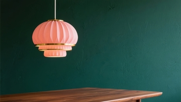 粉色多层吊灯悬挂在绿色墙壁旁的木质桌面上
