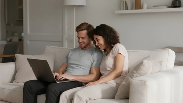 一对男女在客厅沙发上使用笔记本电脑互动