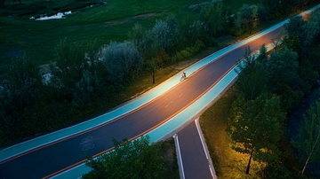 夜晚公路上骑行者光影交错的空中俯瞰画面