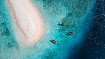 俯瞰热带岛屿沙滩与碧蓝海水中的小船