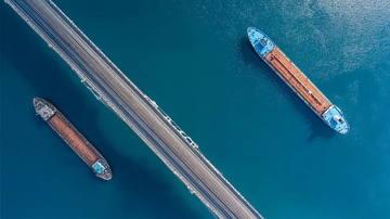 俯瞰视角下三艘货船在蓝色海域中航行