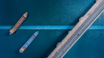 俯瞰视角下桥梁与货船在蓝色水域中的景象