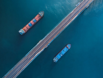 航拍视角下桥梁旁的两艘货船