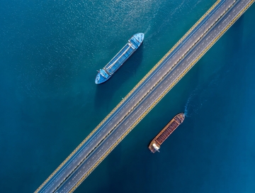 航拍视角下两艘货船在蓝色水域中航行