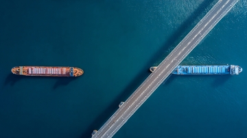 两艘货船在桥梁下航行于深蓝色水域