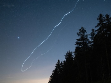 夜空中的光轨与森林剪影