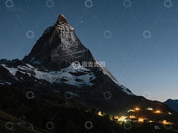 夜幕下的雄伟山峰与灯火村庄