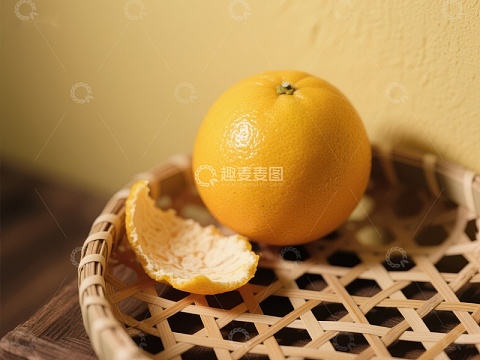 新鲜橙子置于竹篮，部分剥皮