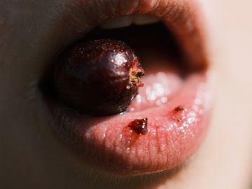 嘴唇轻咬红色浆果的特写