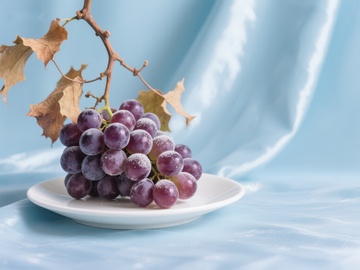 盘中紫葡萄与秋叶的静物组合
